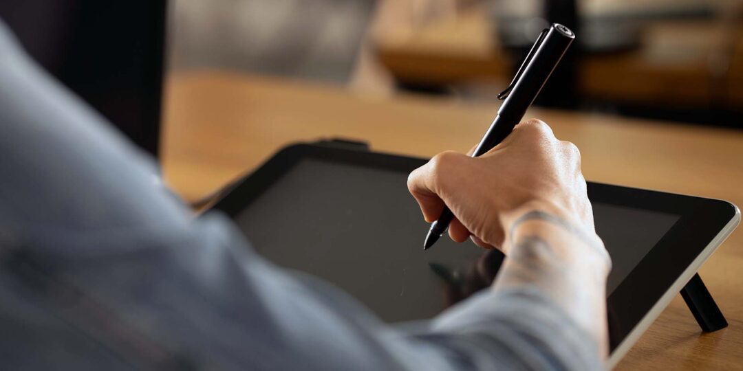 A person using Wacom Cintiq pen display and Adobe Illustrator