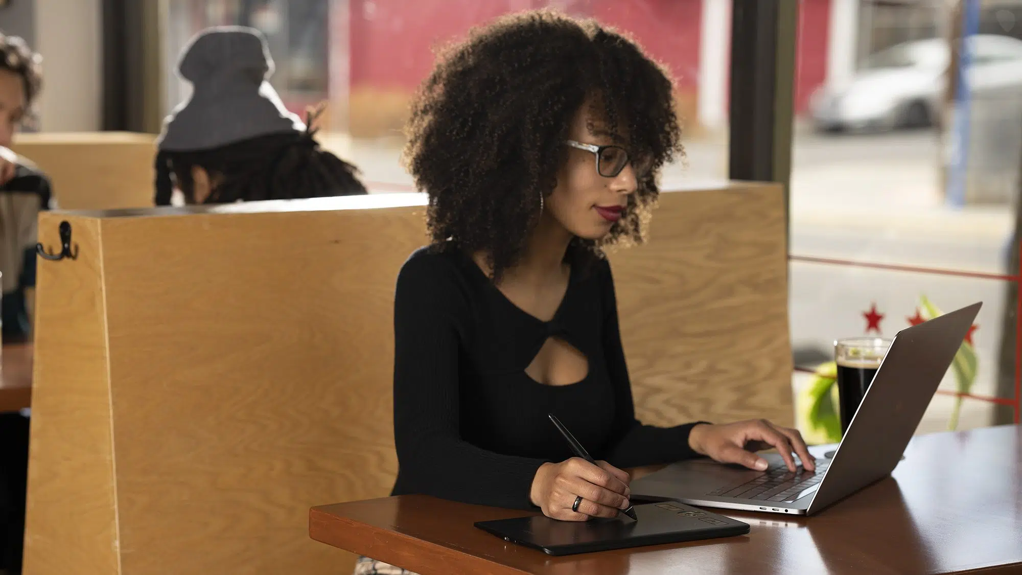 Mulher negra usando Wacom Intuos Pro em uma cafeteria